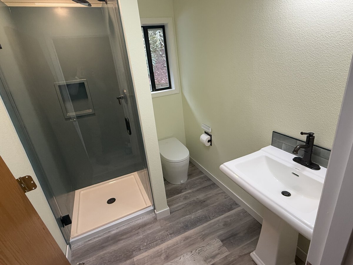 Full view of compact custom bathroom with shower, toilet, and pedestal sink by Righteous Renovations in Salem, OR