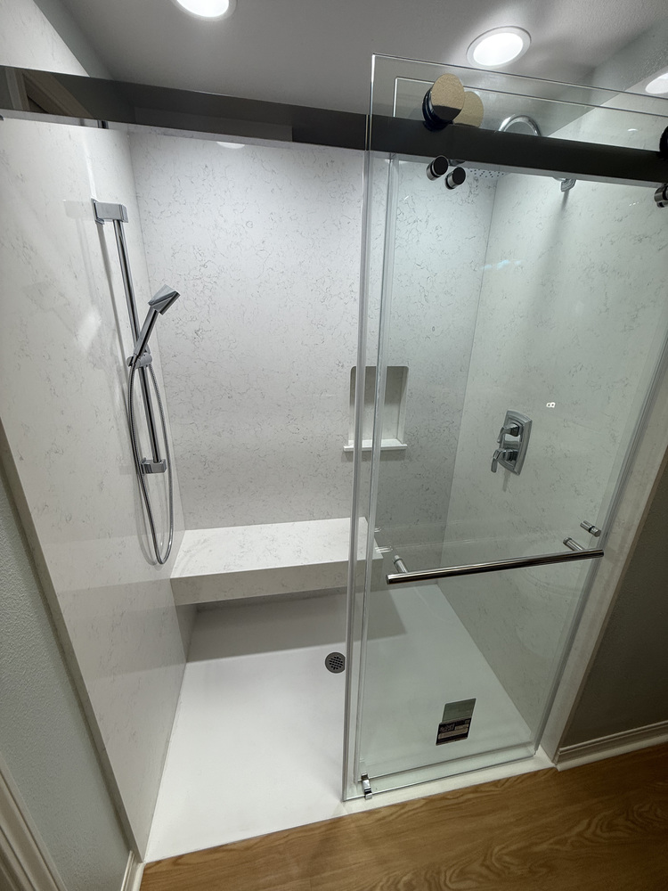 Modern shower remodel featuring a built-in bench and sliding glass doors by Righteous Renovations in Salem, Oregon