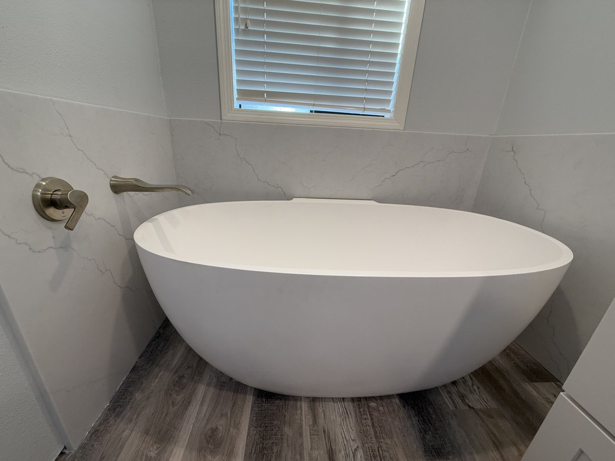 Oval soaking tub with wall-mounted faucet in custom home bathroom by Righteous Renovations in Salem, OR
