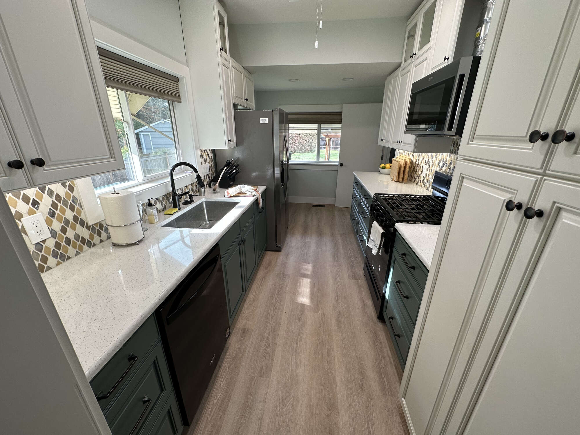 Full view of galley-style kitchen with quartz counters and wood-look floors by Righteous Renovations in Salem, OR