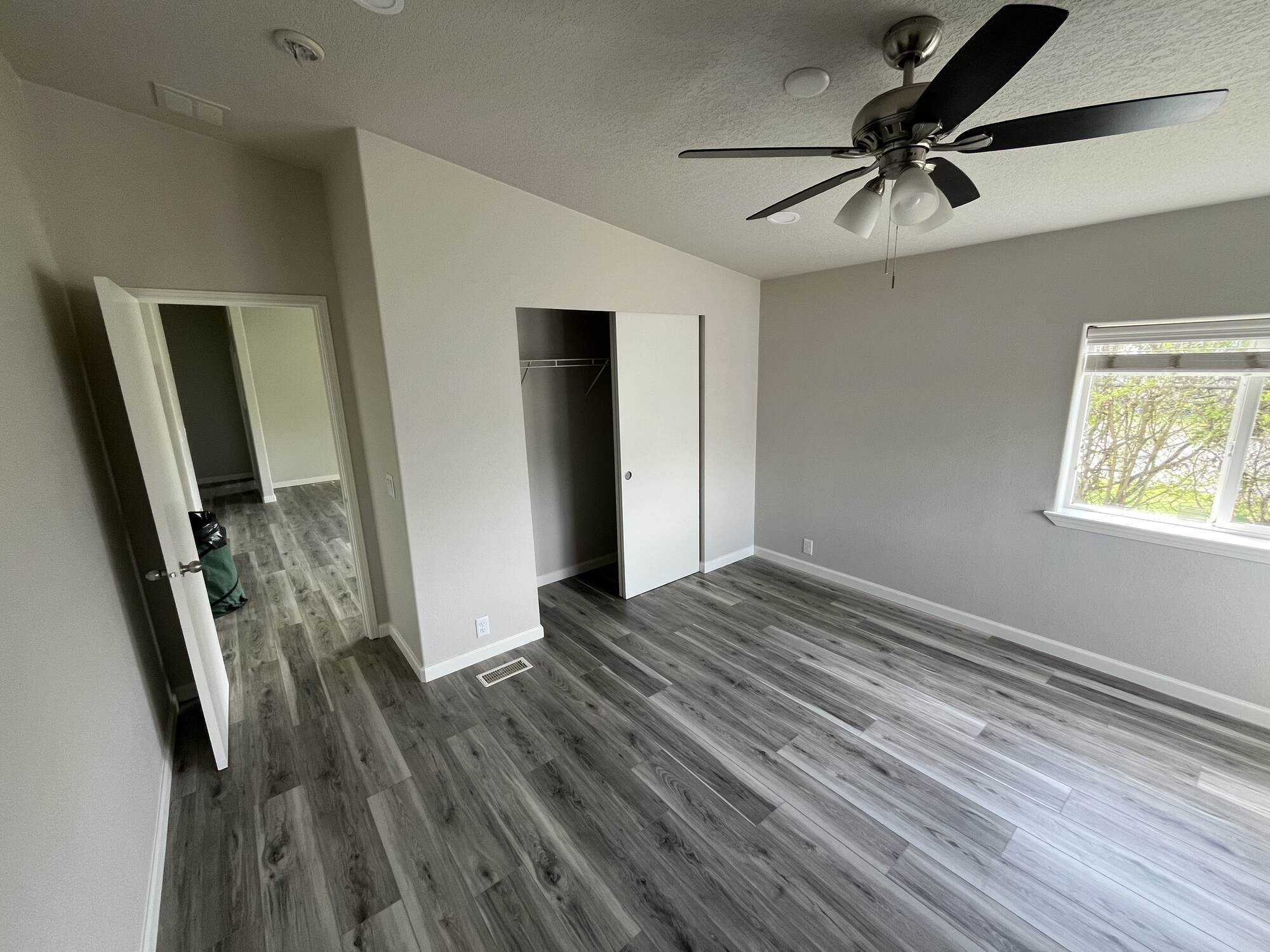Renovated bedroom with vinyl plank flooring and ceiling fan by Righteous Renovations in Salem, OR