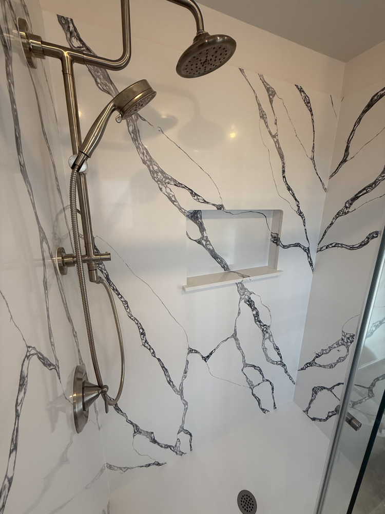 Detailed look at dual showerheads and dramatic veined wall surface by Righteous Renovations in a Salem, Oregon custom home