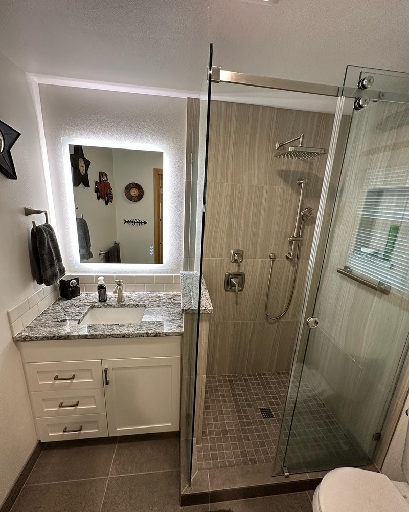 Bathroom remodel with LED mirror, granite vanity, and frameless glass shower by Righteous Renovations in Salem, OR