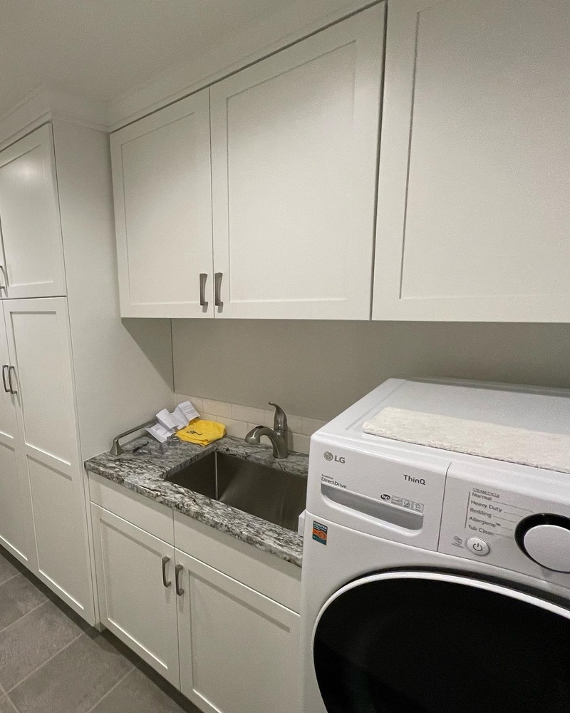 Close-up of modern laundry area with utility sink and granite surface by Righteous Renovations in Salem, OR