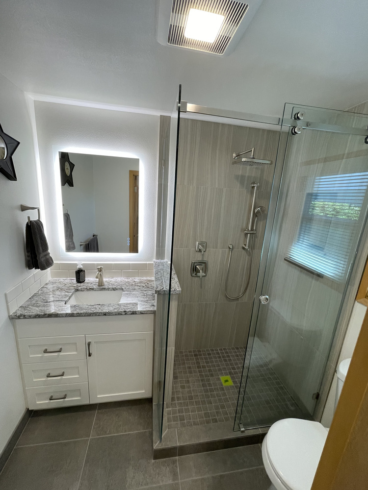 Modern bathroom with single-sink vanity and frameless shower door in Salem, Oregon by Righteous Renovations