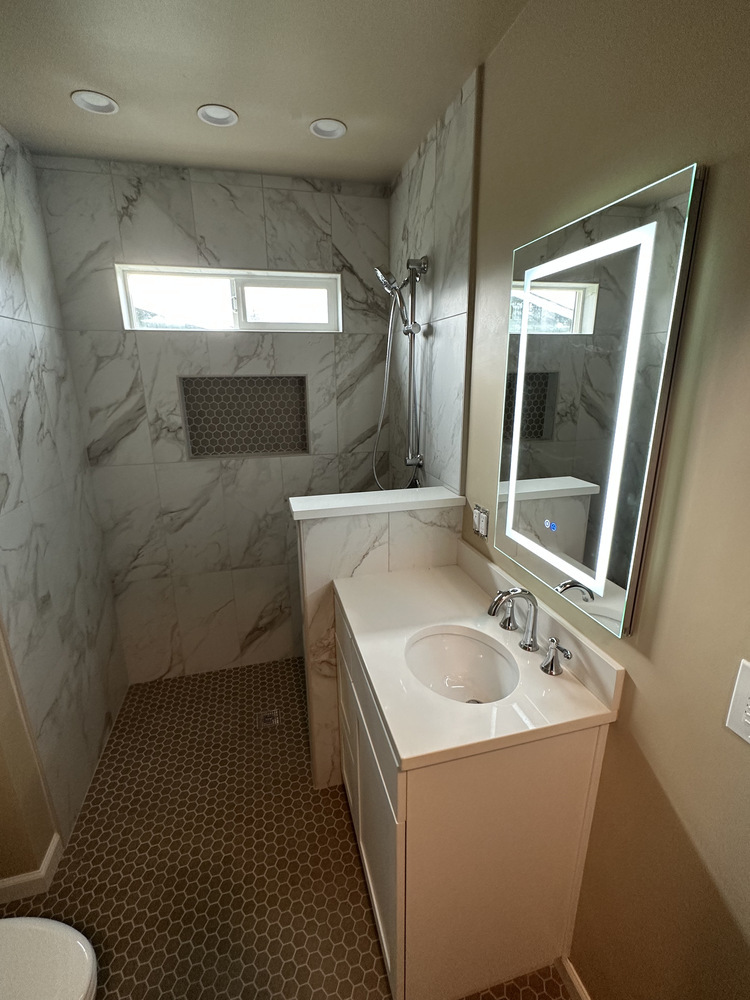 Accessible bathroom design with wall-mounted sink and white storage cabinet by Righteous Renovations in Salem, Oregon