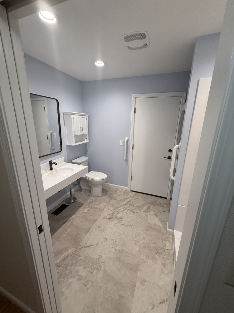 Overview of accessible bathroom design with open floor space and soft blue wall paint by Righteous Renovations in Salem, OR
