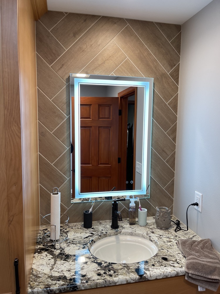 Granite bathroom counter with illuminated mirror and modern fixtures by Righteous Renovations in Newberg, OR
