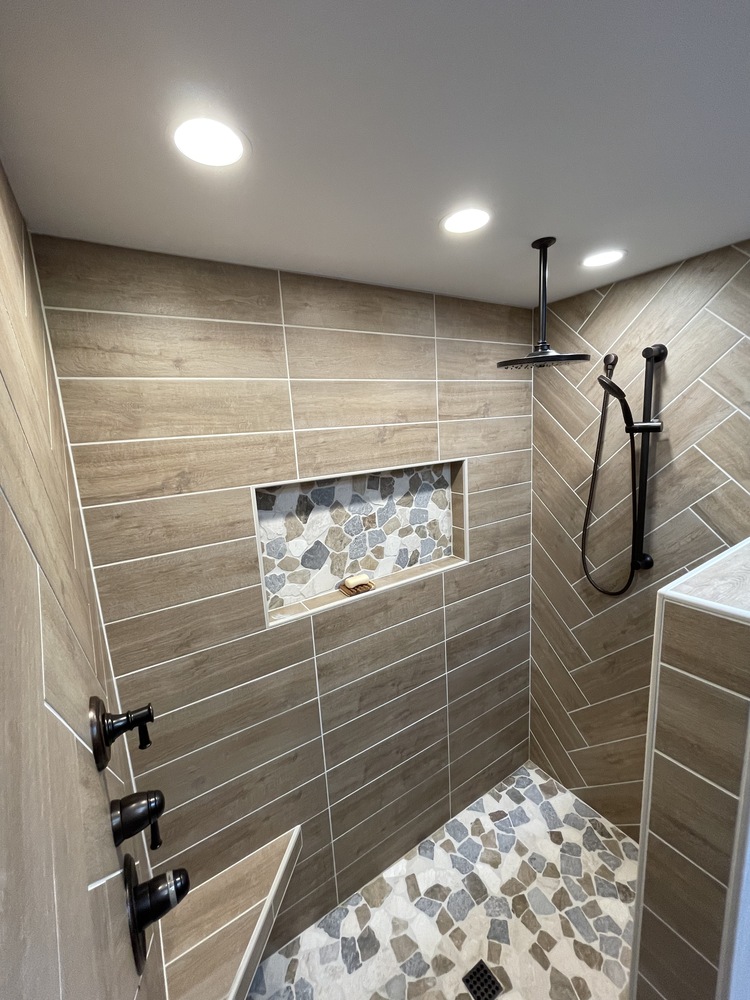 Modern walk-in shower with wood-look tile and stone mosaic floor by Righteous Renovations in Corvallis, OR