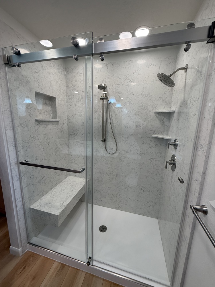 Frameless glass shower with built-in bench and marble walls by Righteous Renovations in Newberg, OR