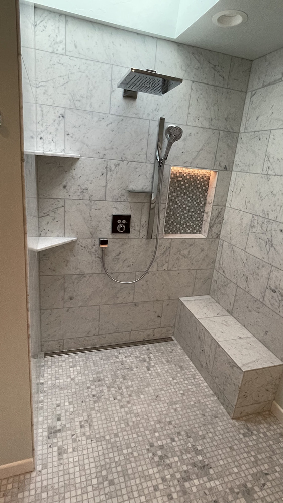 Marble-tiled shower with built-in bench and niche lighting in a Righteous Renovations bathroom remodel in Silverton, OR