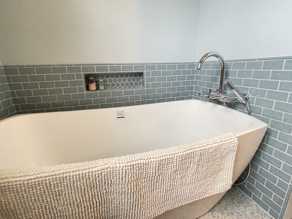 Deep soaking tub with tiled backsplash and built-in shelving in a custom home bathroom by Righteous Renovations in Salem, OR