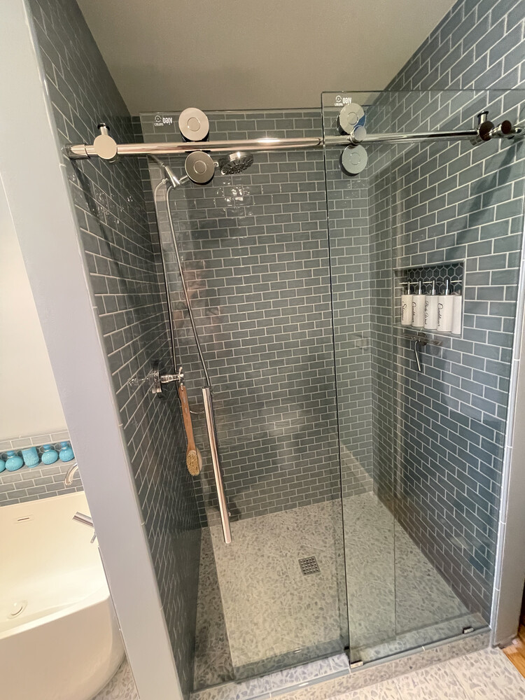 Glass-enclosed walk-in shower with chrome hardware and gray subway tile by Righteous Renovations in Salem, OR