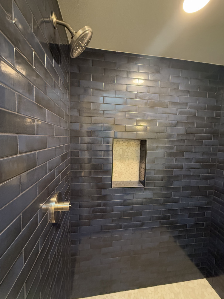 Overhead view of walk-in shower with dark tile and recessed niche by Righteous Renovations in Salem, OR