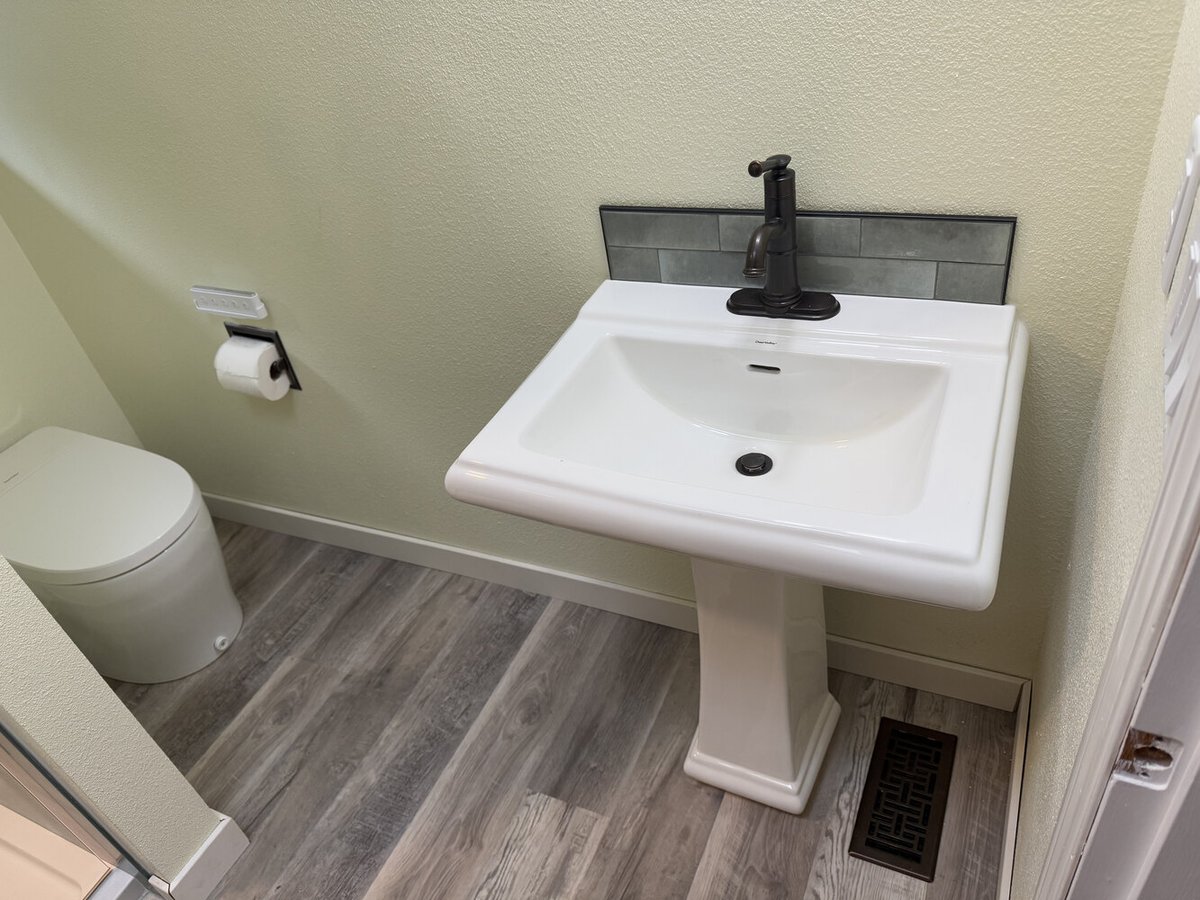 Pedestal sink with black faucet and subway tile backsplash in custom bathroom by Righteous Renovations in Salem, OR