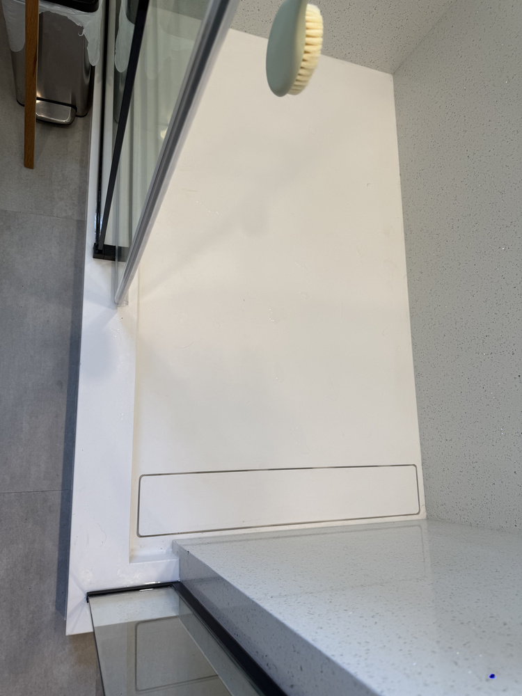 Close-up of custom linear shower drain and quartz ledge by Righteous Renovations in Salem, OR