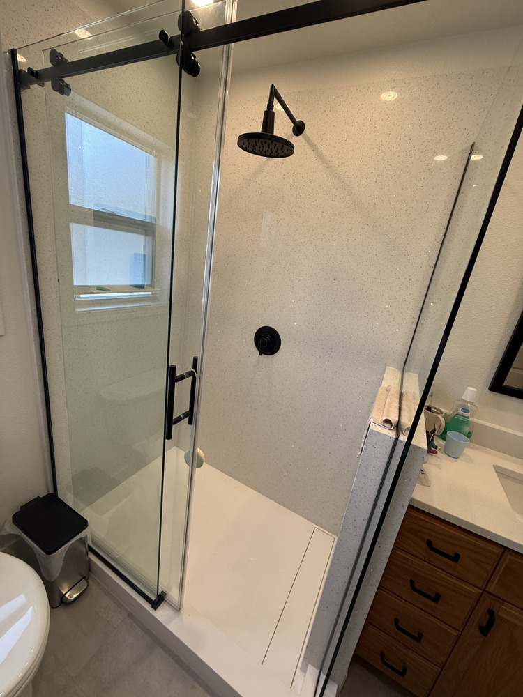 Frameless glass shower with matte black rain showerhead in custom bathroom by Righteous Renovations in Salem, OR