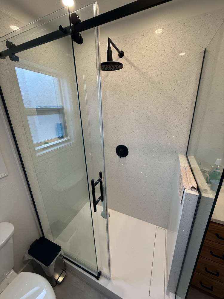 Frameless sliding shower door with matte black hardware in custom bathroom by Righteous Renovations in Salem, OR