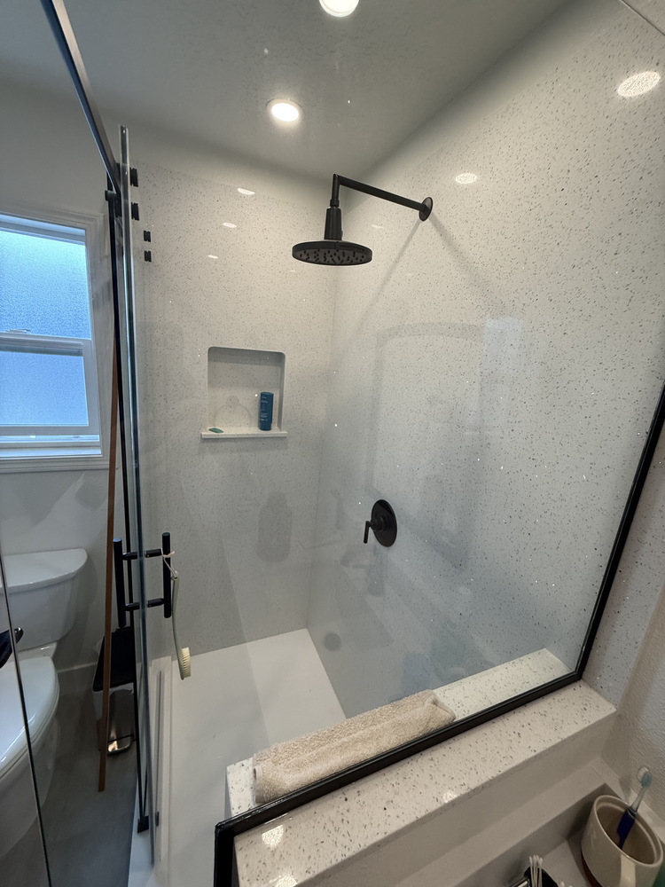 Matte black rain shower and built-in shelf in modern Salem, Oregon bathroom by Righteous Renovations