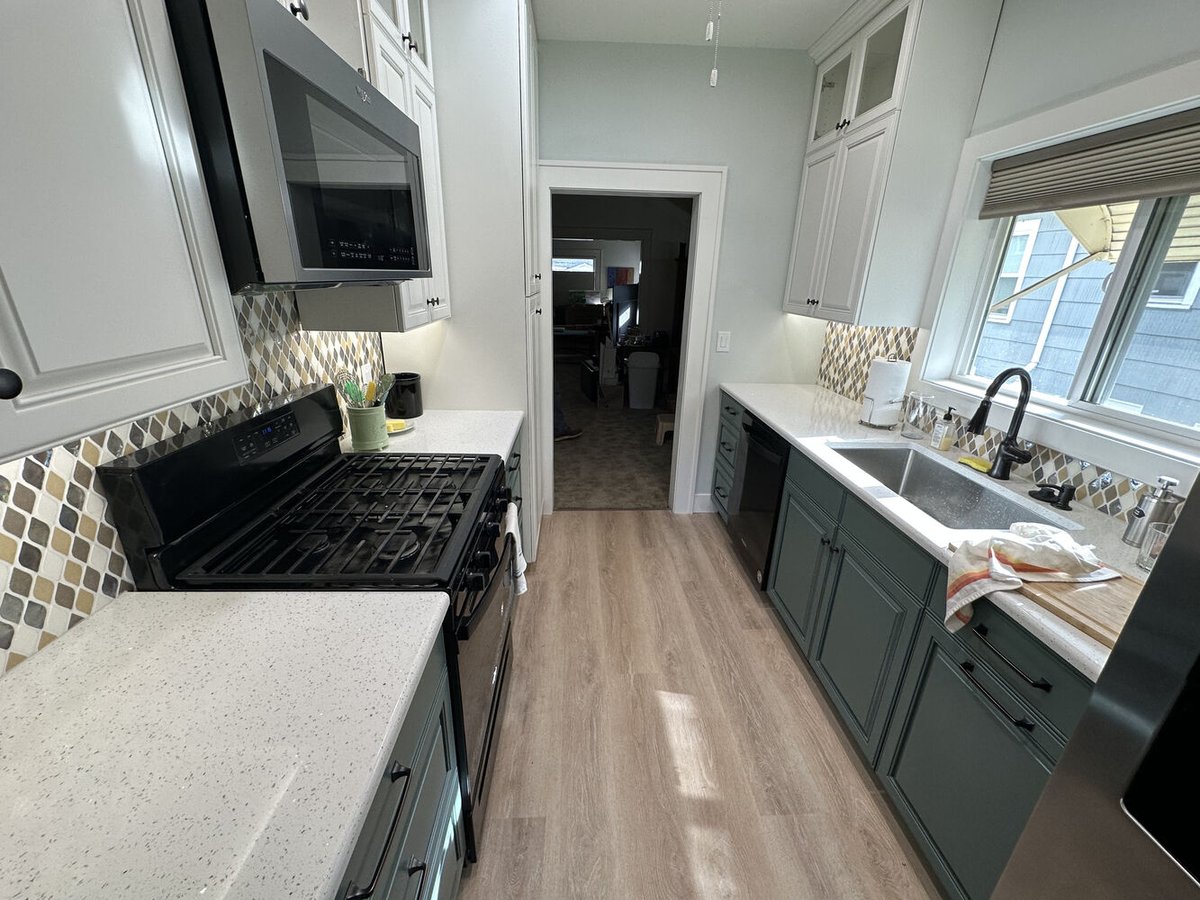 Kitchen view with black stove, white cabinets, and mosaic backsplash by Righteous Renovations in Salem, OR