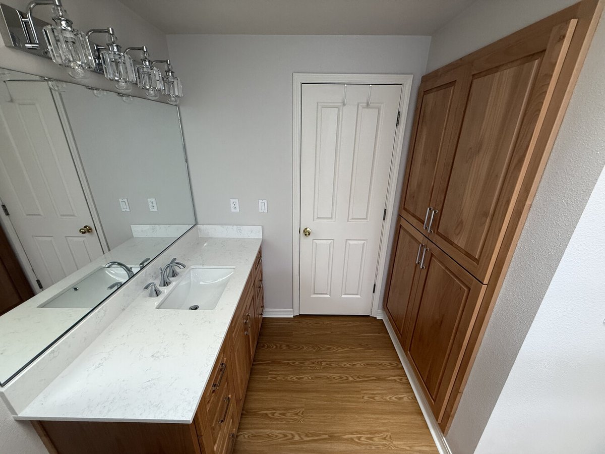 Long view of a remodeled bathroom with double-door storage and wood vanity by Righteous Renovations in Salem, Oregon