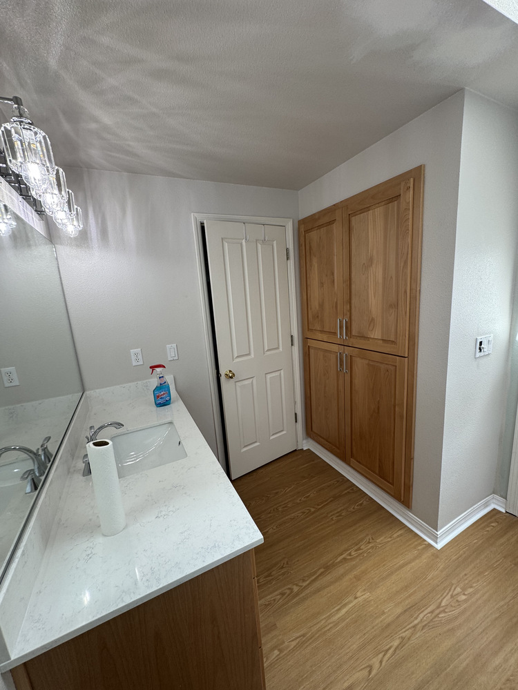 Sleek bathroom with built-in storage and white countertop designed by Righteous Renovations in a custom Salem home