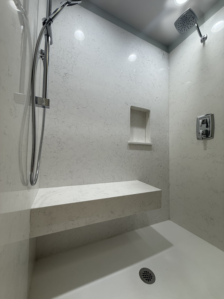 Sleek white walk-in shower with built-in seating in a Righteous Renovations custom home in Salem, Oregon