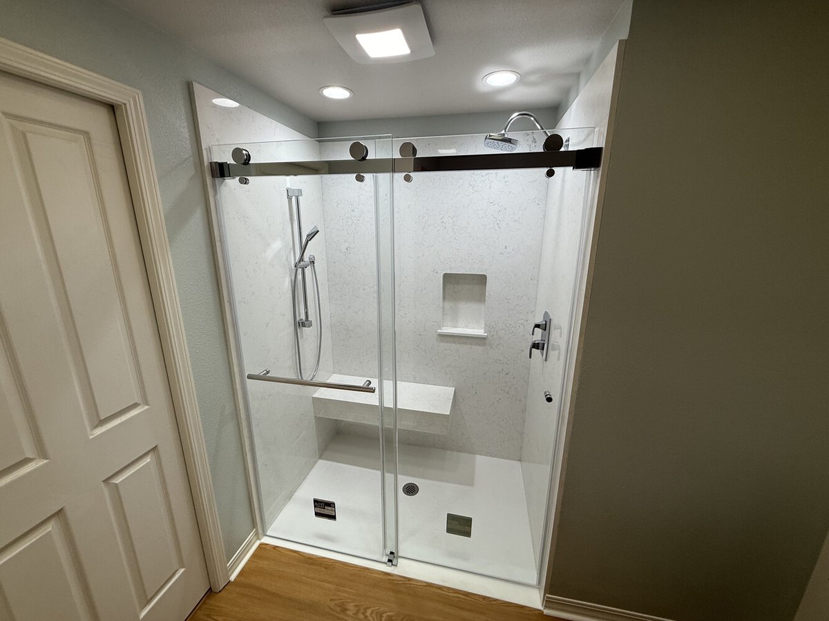 Wide-angle of custom shower remodel with sliding glass doors and built-in quartz bench by Righteous Renovations in Salem, OR