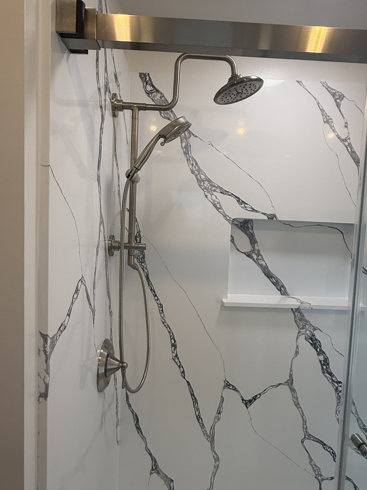 Sleek shower design with stainless fixtures and marble-inspired panels by Righteous Renovations in Salem, Oregon