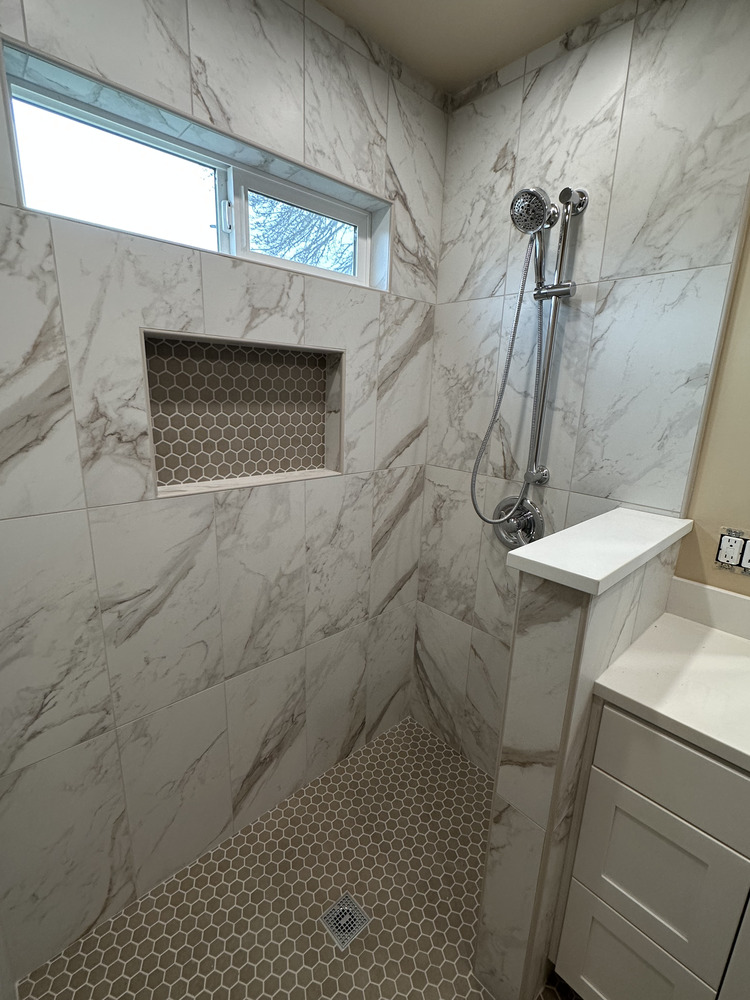 Entry view into accessible bathroom with wide doorway and light marble flooring by Righteous Renovations in Salem, OR