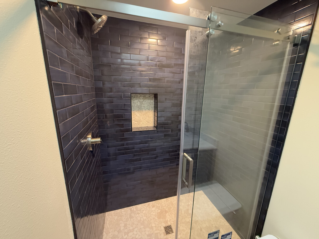 Walk-in shower with glass door and dark tile walls in a Salem, OR custom home by Righteous Renovations