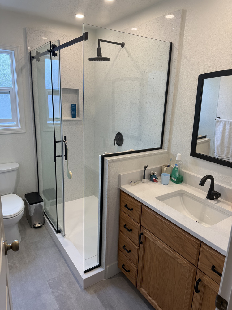 Modern bathroom remodel with black-framed mirror and sliding shower door in Salem, Oregon by Righteous Renovations