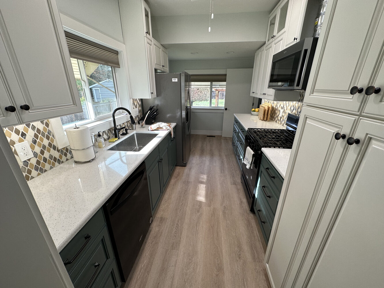 Full view of galley-style kitchen with quartz counters and wood-look floors by Righteous Renovations in Salem, OR
