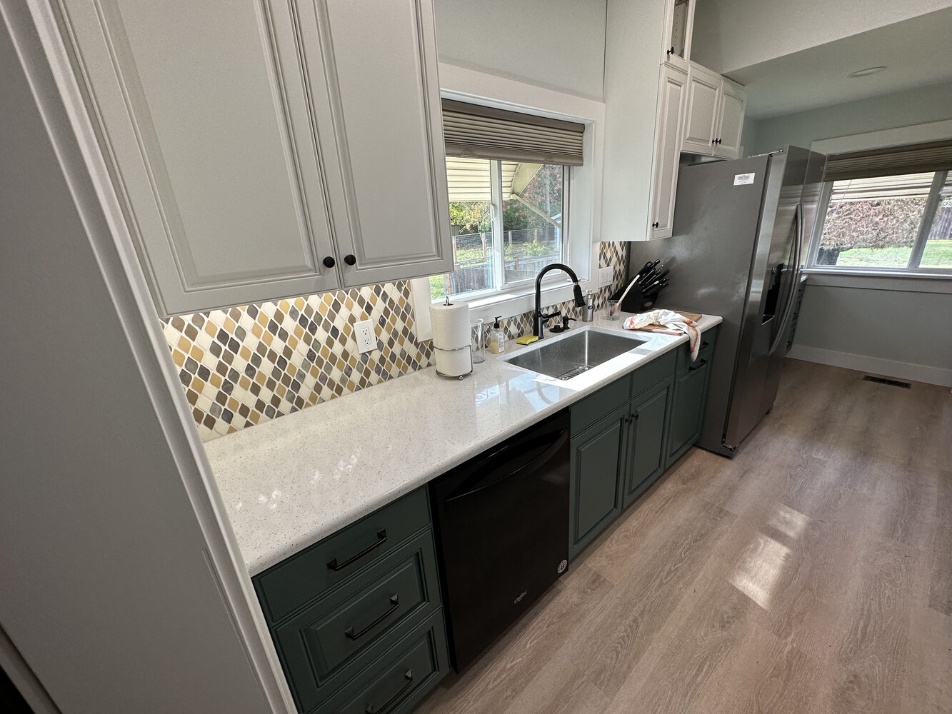 Side view of remodeled kitchen with green cabinetry and large window by Righteous Renovations in Salem, OR