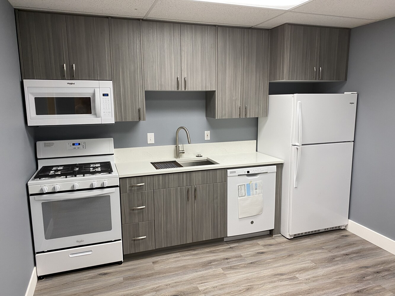 Modern compact kitchen remodel with gray slab cabinets and white appliances by Righteous Renovations in Salem, OR